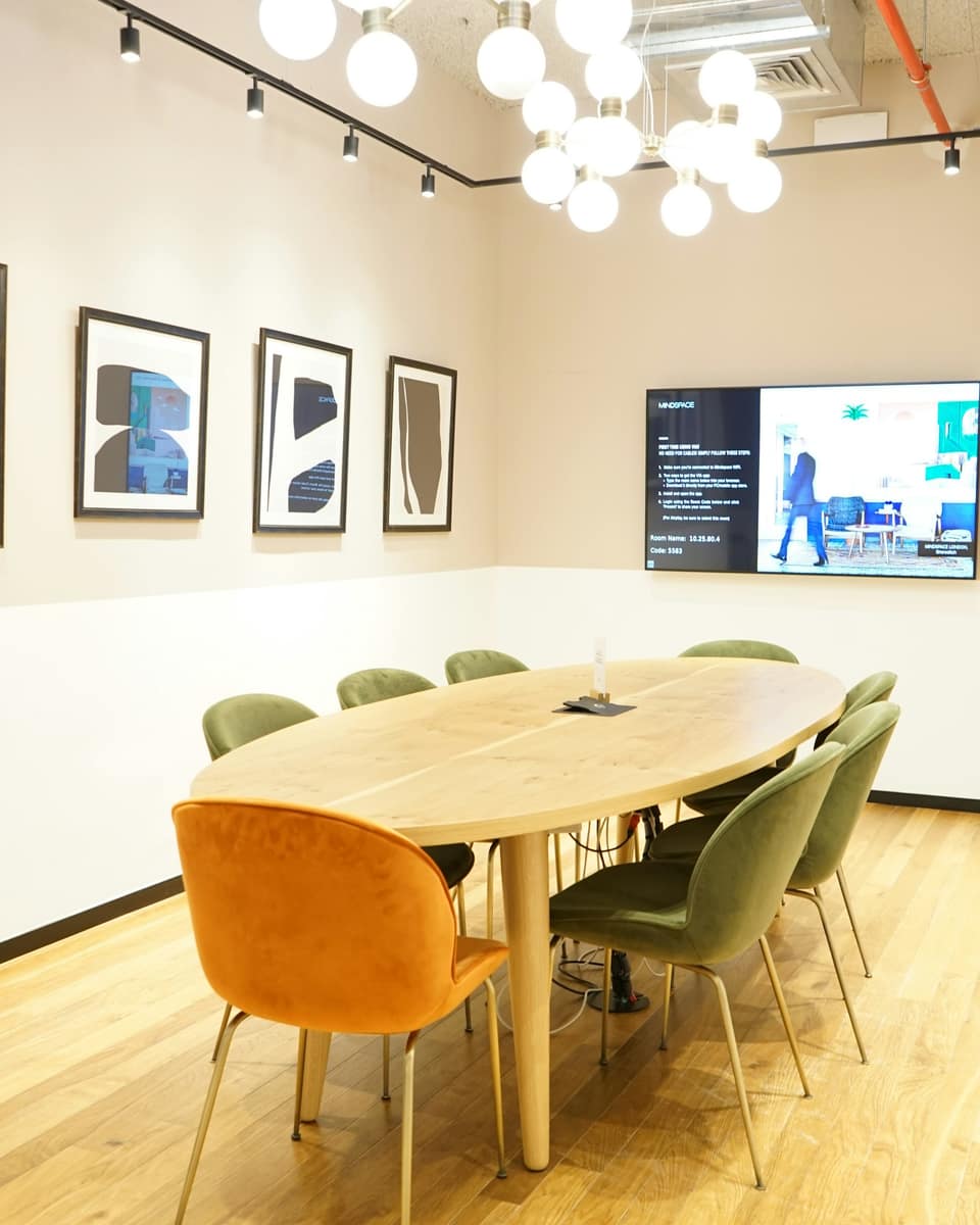 Meeting room with an oval wooden table and a wall screen