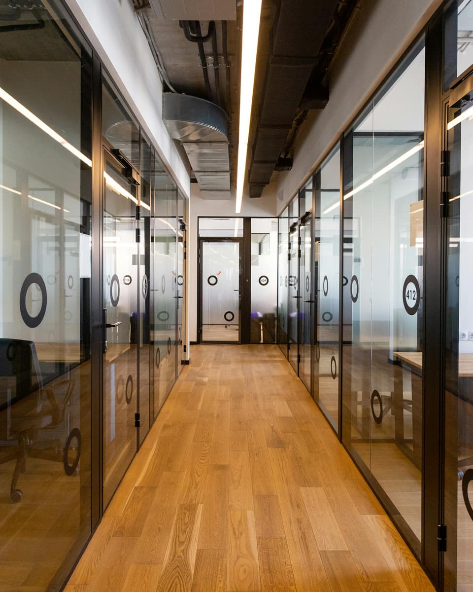 Wooden-floored corridor lined with glass office doors